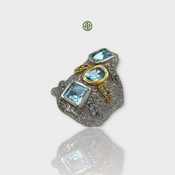 A silver ring featuring multiple square-shaped aqua marine stones, with gold vermeil and white rhodium plating.