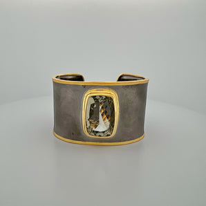 Luxury green amethyst cuff bangle crafted in black rhodium plated 925 sterling silver with thick 18K gold vermeil bezel. Elegant wide statement bracelet adjustable for 16–17 cm wrists.