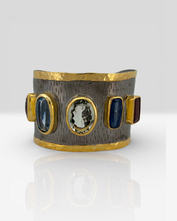 Luxury wide cuff bangle crafted from black rhodium plated 925 sterling silver with thick 18K gold vermeil. Featuring Green Amethyst, Kyanite, Tourmaline, Blue Topaz and Amethyst gemstones. Adjustable statement bracelet for 16–17cm wrists.