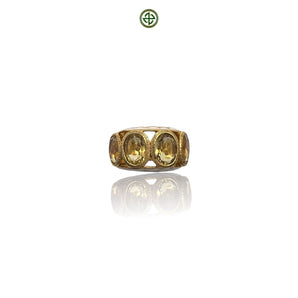 A gold-colored ring with four citrine stones arranged in a line, set against a white background.