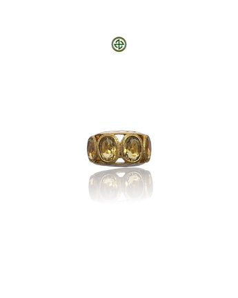 A gold-colored ring with four citrine stones arranged in a line, set against a white background.
