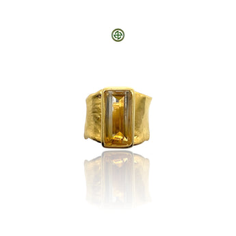 A gold-colored ring featuring a rectangular citrine gemstone set in a smooth bezel, with a textured band.