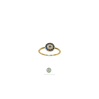 A gold-colored band ring with a round blue and white zirconia stone centerpiece, presented against a white background.