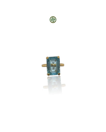 An emerald-cut blue topaz ring with a gold vermeil band on a white background.