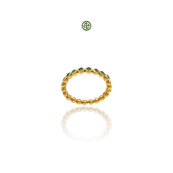 A gold-colored stacking band ring with emerald stones evenly spaced around its circumference, displayed against a white background.