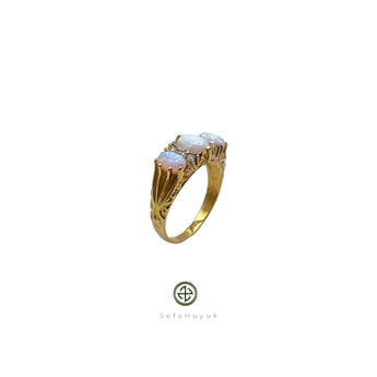 A gold-plated ring featuring an iridescent opal center stone with two additional opal inlays on the sides, set on a white background.