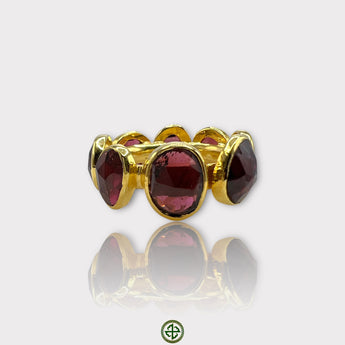 A gold vermeil eternity ring set with natural garnets, displayed against a white background.