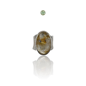 A golden rutilated quartz ring with a white rhodium-plated band, displayed on a reflective surface.
