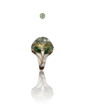An ornate silver ring featuring a green amethyst center stone with enamel details, displayed against a white background.