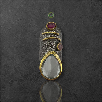 A silver ring featuring a green amethyst, a ruby, and a pink tourmaline gemstone, with gold vermeil detailing.
