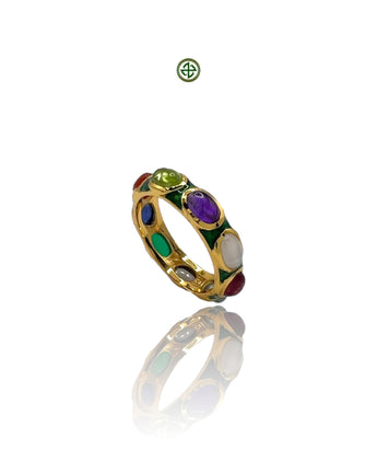 A gold vermeil eternity ring with multiple gemstones set in a green enamel band, displayed on a reflective surface.