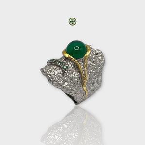 A silver ring featuring a central green onyx gemstone with gold vermeil detailing and flanked by smaller emerald stones.