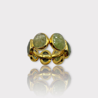 A gold-colored eternity ring with green tourmaline stones set in a silver band, viewed from the side.