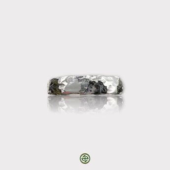 A silver band ring featuring a raw black tourmaline and raw peridot gemstone set