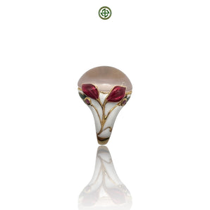 A rose quartz center stone ring with red and white enamel floral patterns and small ruby side stones, gold vermeil plating, displayed against a white background.