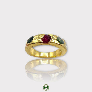 A gold-colored band ring featuring a central ruby with green tourmaline on either side, set in a textured setting.