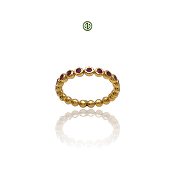 A gold-colored band ring with round cut ruby stones arranged in a stacking design.
