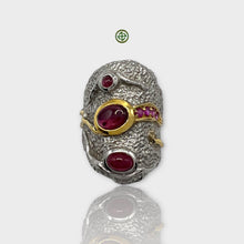 A handcrafted silver ring with multiple oval and round red ruby gemstones set in a textured band with a gold accent.