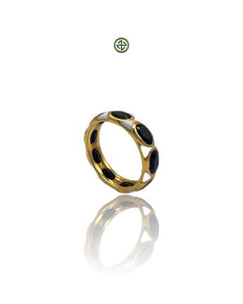 A gold-colored eternity ring with blue sapphire stones and white enamel inlay, displayed on a reflective surface.