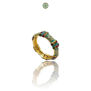 A gold vermeil ring with turquoise enamel and inlaid stones, displayed against a reflective background.