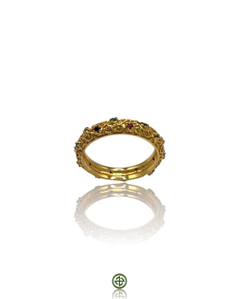 A gold-colored eternity ring with alternating ruby, emerald, and sapphire stones set in a continuous band.