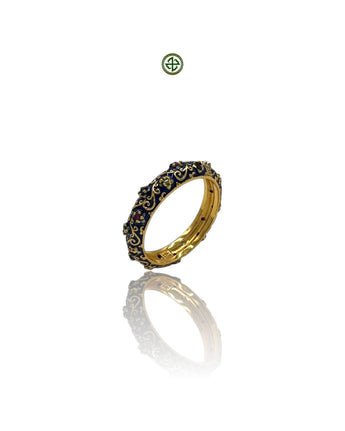 A navy blue enamel eternity ring with gold plating and inlaid with ruby, emerald, and sapphire stones, displayed on a reflective surface.