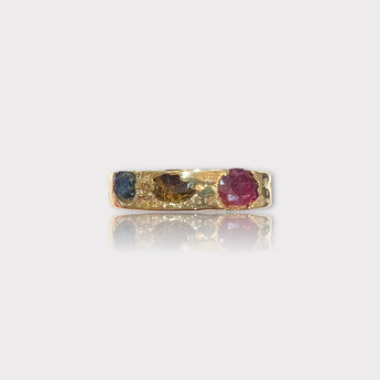 A gold vermeil band ring featuring a raw peridot gemstone alongside rubies and other tourmalines.