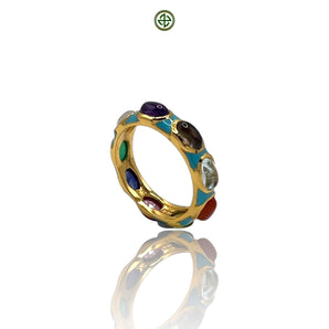 A gold-colored eternity ring with multiple colorful gemstones and turquoise enamel detailing, displayed against a reflective background.