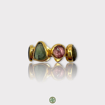 A multicolored tourmaline stone set in a gold-colored band, designed as an eternity ring.