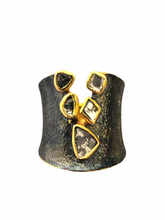 A black rhodium-plated band ring with gold vermeil trimmings, featuring a line of raw diamonds.