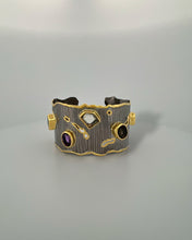 Luxury gemstone cuff bangle crafted in black rhodium plated 925 sterling silver with thick 18K gold vermeil. Featuring Green Tourmaline, Amethyst, Lemon Quartz, Smoky Quartz and Yellow Tourmaline. Adjustable statement bracelet for 16–17 cm wrists.
