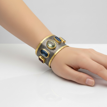 Luxury wide cuff bangle crafted from black rhodium plated 925 sterling silver with thick 18K gold vermeil. Featuring Green Amethyst, Kyanite, Tourmaline, Blue Topaz and Amethyst gemstones. Adjustable statement bracelet for 16–18 cm wrists.
