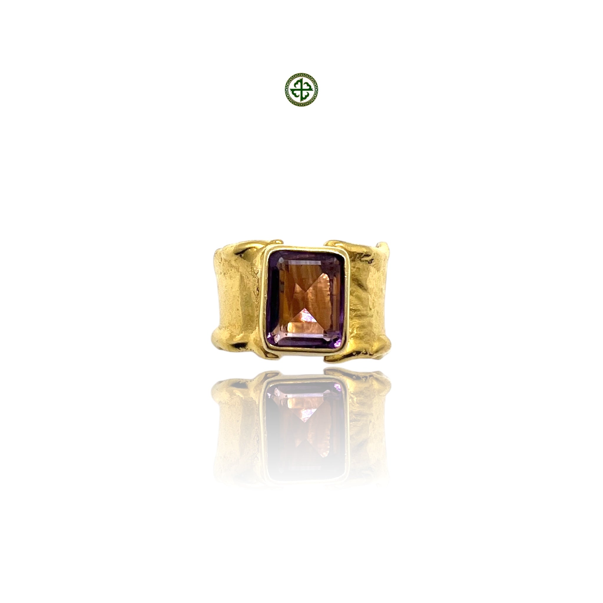 A gold-colored ring with a rectangular amethyst stone set in a smooth bezel, displayed against a white background.