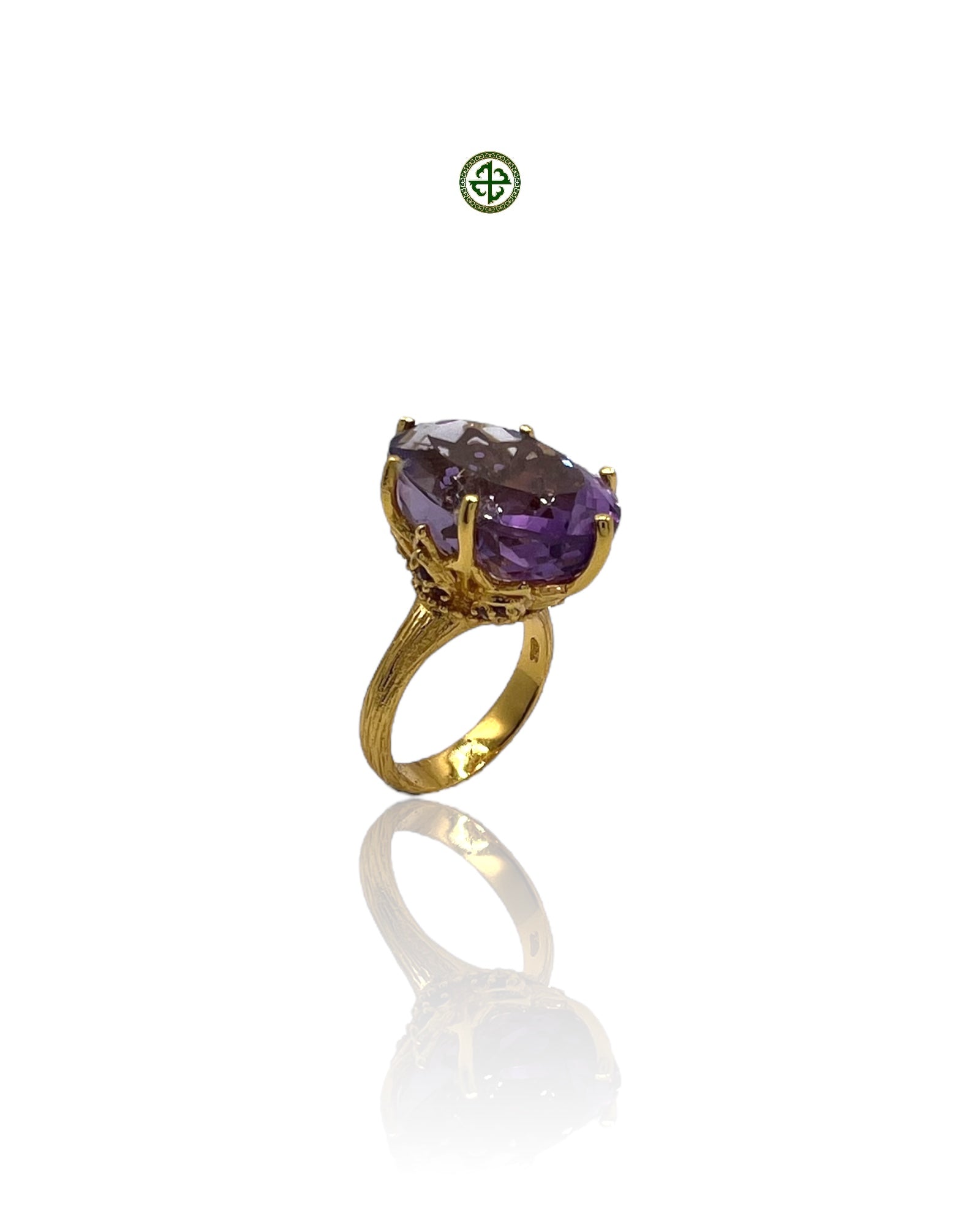 A gold-colored ring with a large amethyst center stone, surrounded by smaller amethysts, displayed against a white background.