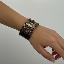 Luxury cuff bangle crafted in black rhodium plated 925 sterling silver with thick 18K gold vermeil. Featuring a marquise green amethyst centerpiece surrounded by garnet gemstones. Adjustable statement bracelet for 16–17 cm wrists.
