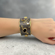 Luxury gemstone cuff bangle crafted in black rhodium plated 925 sterling silver with thick 18K gold vermeil. Featuring Green Tourmaline, Amethyst, Lemon Quartz, Smoky Quartz and Yellow Tourmaline. Adjustable statement bracelet for 16–17 cm wrists.