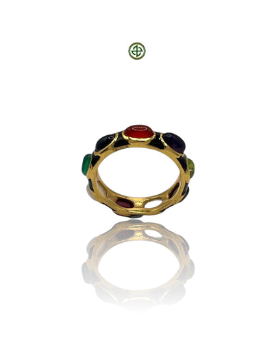 A gold-colored eternity ring with multiple colored gemstones set in black enamel, displayed on a reflective surface.