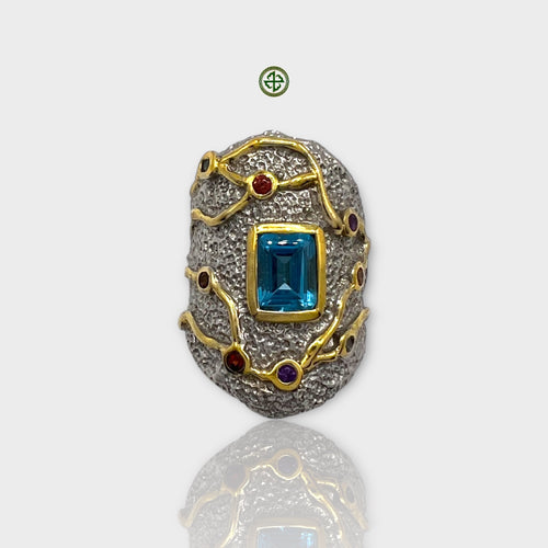 A detailed image of a Blue Topaz natural stone ring with gold and silver plating, featuring multiple colored gemstones.