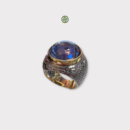 A rose quartz statement ring with a blue topaz gemstone, featuring a gold vermeil and black rhodium plating on a silver band.