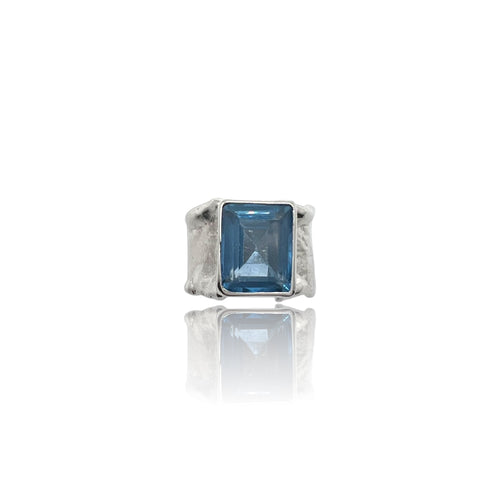 A blue topaz ring with a white rhodium plating on a silver band, displayed against a white background.