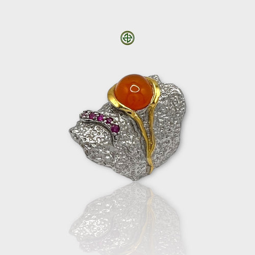 A carnelian silver ring with gold vermeil and white rhodium plating, featuring a large central carnelian stone with smaller ruby stones on the sides, displayed against a white background.