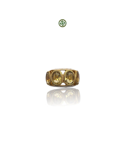 A gold-colored ring with four citrine stones arranged in a line, set against a white background.