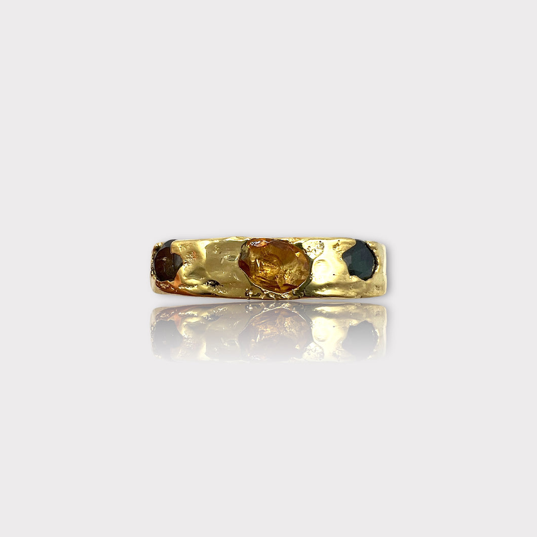 A gold vermeil band ring featuring a raw and natural uncut gemstone, with colors yellow, green, and blue, set in a textured setting.