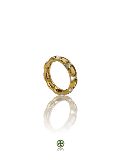 A gold-colored eternity ring with white enamel inlay and citrine stones, displayed on a reflective surface.