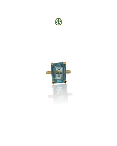 An emerald-cut blue topaz ring with a gold vermeil band on a white background.