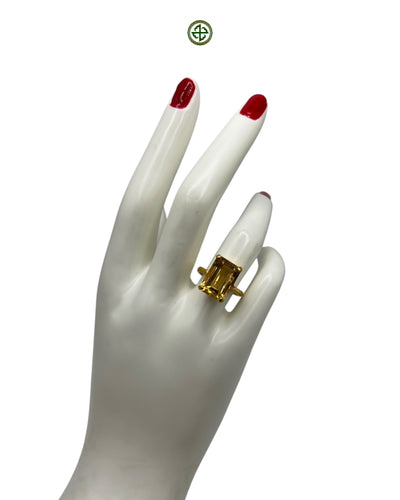 An emerald-cut citrine ring with gold plating on a white mannequin hand.