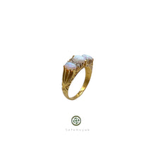 A gold-plated ring featuring an iridescent opal center stone with two additional opal inlays on the sides, set on a white background.