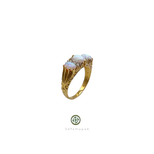 A gold-plated ring featuring an iridescent opal center stone with two additional opal inlays on the sides, set on a white background.