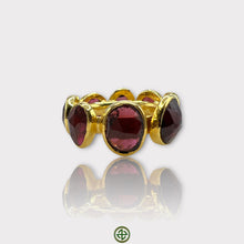A gold vermeil eternity ring set with natural garnets, displayed against a white background.