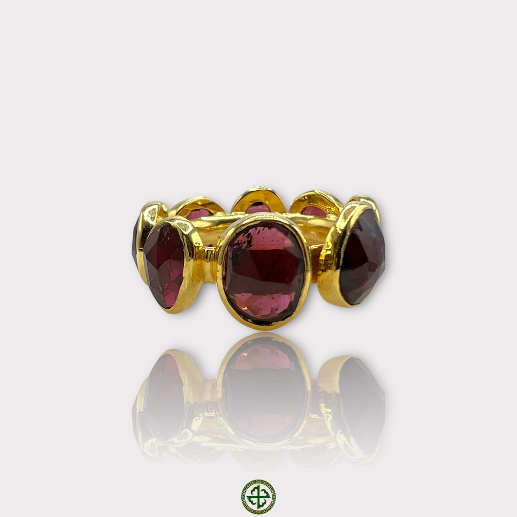 A gold vermeil eternity ring set with natural garnets, displayed against a white background.